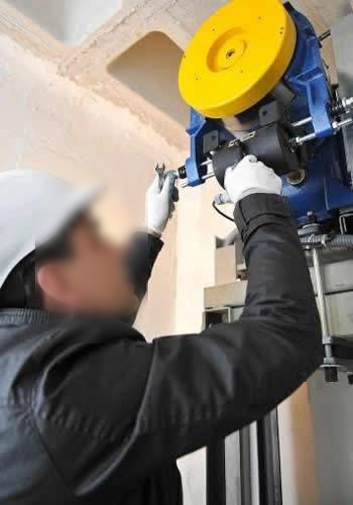 T&eacute;cnico con casco y guantes trabajando sobre el equipo de un ascensor