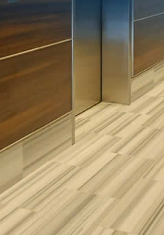 Interior de cabina de ascensor con acabados en madera y piso renovado