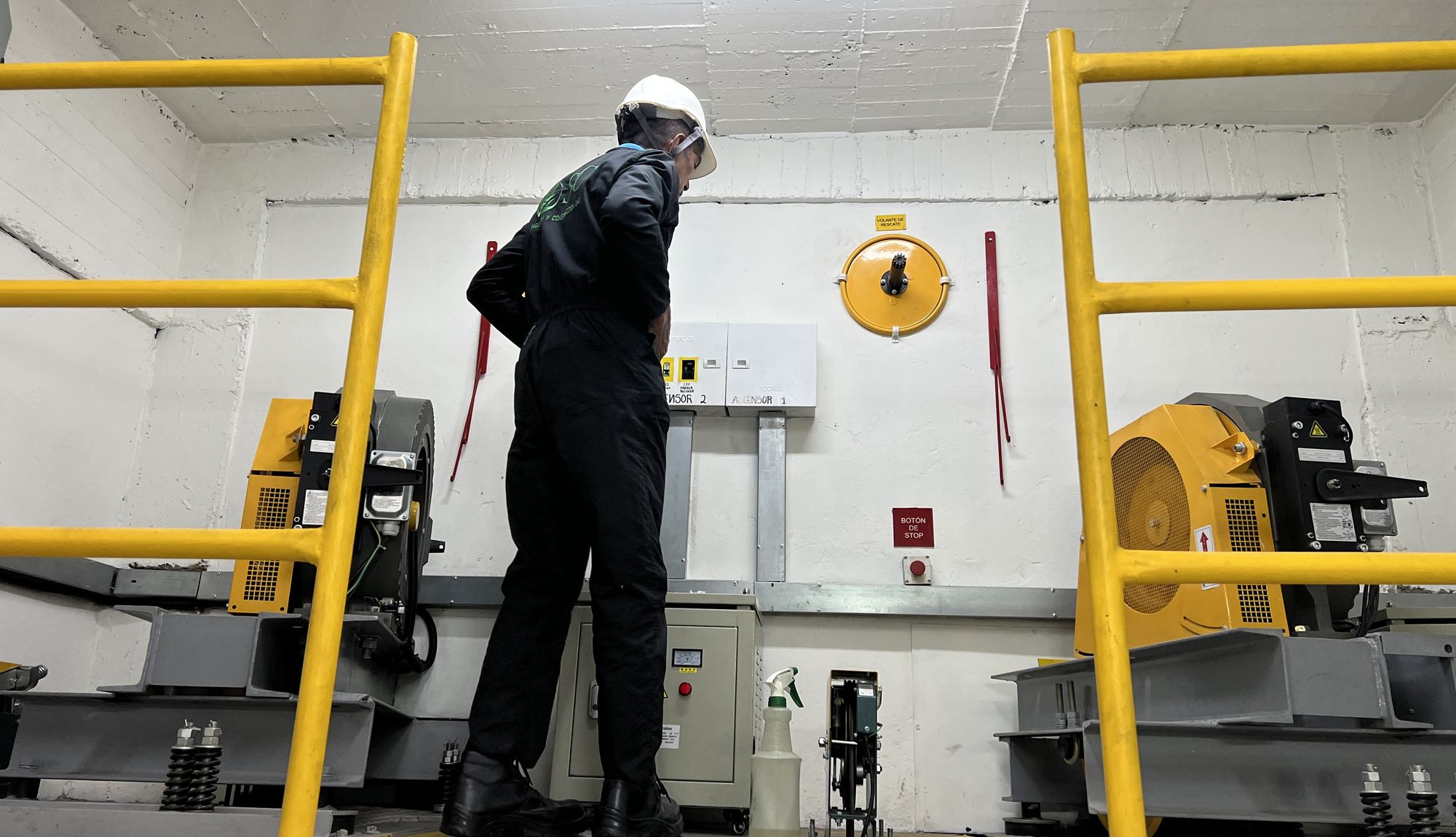 T&eacute;cnico de Elevascensor con casco revisando las m&aacute;quinas de tracci&oacute;n en el cuarto de m&aacute;quinas de un edificio en Bogot&aacute;