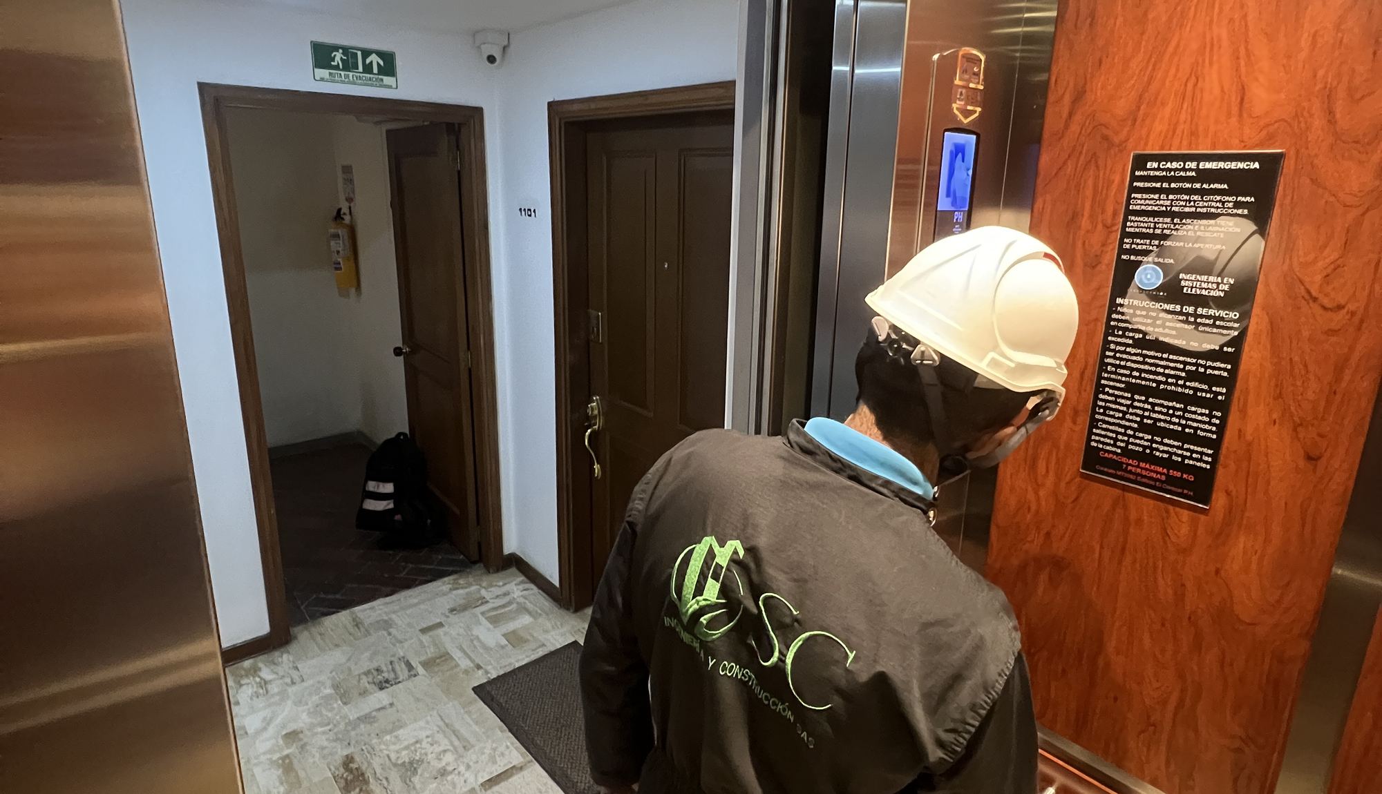 Técnico de Elevascensor con casco frente a la puerta de un ascensor durante una revisión de cabina