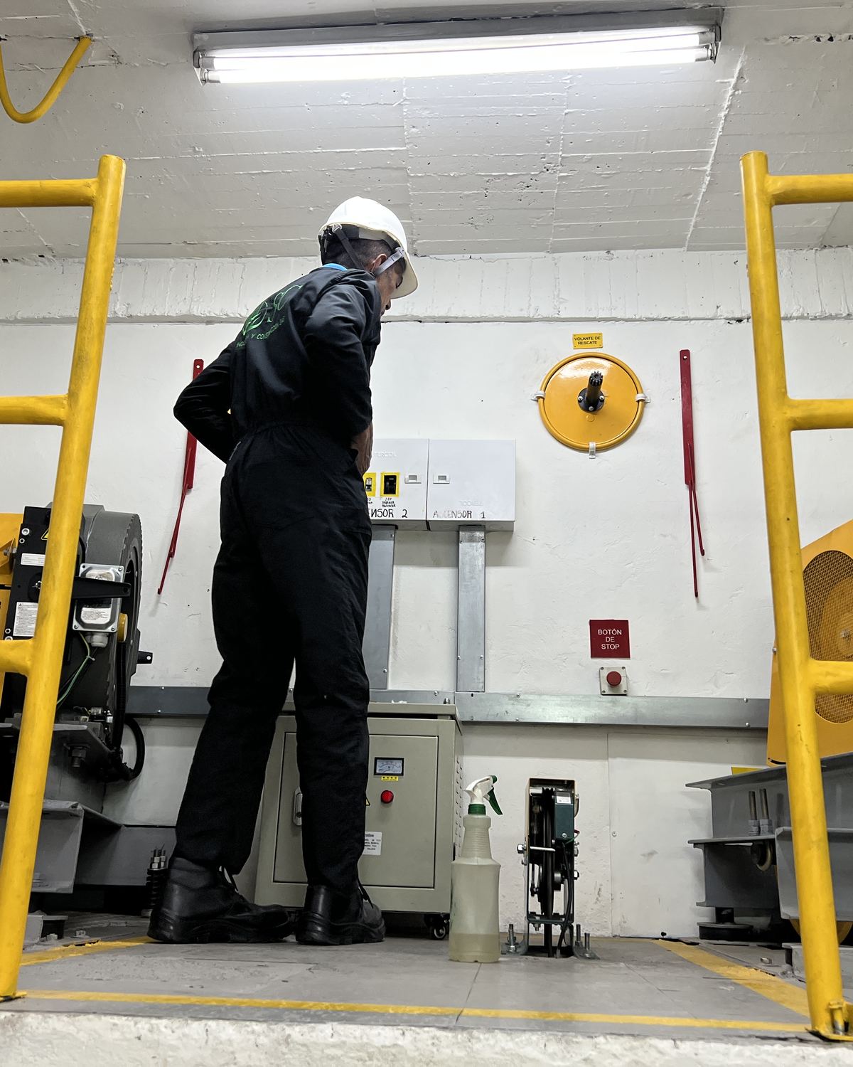 Técnico de Elevascensor revisando el tablero de control en el cuarto de máquinas de un edificio en Bogotá